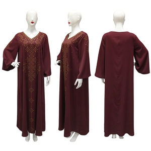 Détails du col en V et des motifs de strass dorés sur la robe caftan bordeaux longue