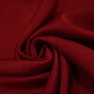 Gros plan sur un tissu satiné bordeaux lisse avec un drapé élégant et une texture soyeuse