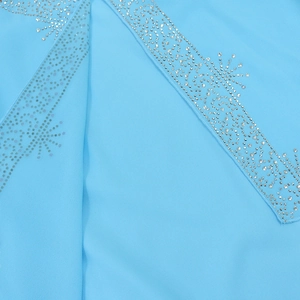 Macro shot of silver rhinestones on light blue chiffon fabric showing detailed embroidery