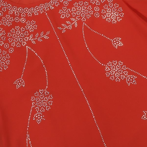 Détail de robe de soirée rouge avec des motifs floraux en strass argentés et décolleté