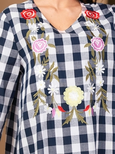 Close-up of colorful floral embroidery and V-neck on blue white gingham dress