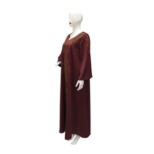 Détail de la broderie géométrique dorée sur le col en V d'une robe abaya bordeaux élégante