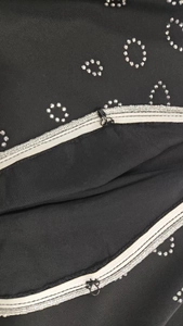 Detailed macro view of silver rhinestones and metal hook on a black dress fabric