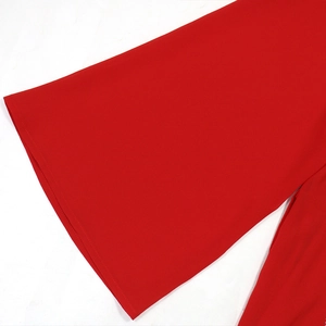 Détail de la robe rouge avec manches cloches larges et finitions de couture fines