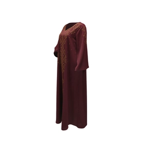Détail d'une robe bordeaux à col en V avec motifs dorés et manches longues amples