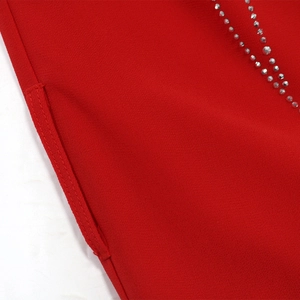 Détail macro d'une robe de soirée rouge montrant les coutures et strass argentés brillants