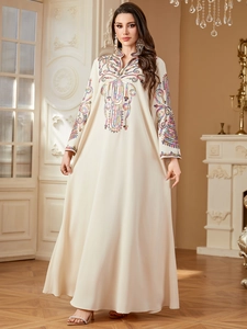 Détail d'une robe caftan crème avec broderies ethniques colorées et paillettes brillantes