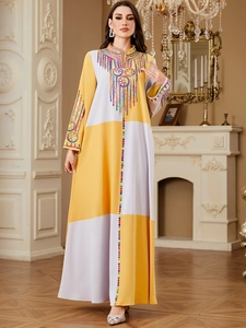 Close-up of elaborate embroidery and sequins on a color-block kaftan dress in yellow and cream