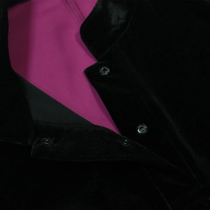 Detail of black velvet robe with vibrant fuchsia lining and round metal snap buttons