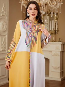 Detail of colorful embroidery and sequins on long-sleeved ginger yellow patchwork robe