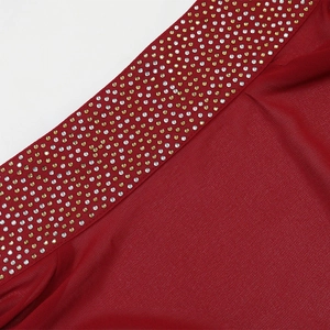 Macro detail of dark red fabric with precise silver and gold rhinestone embellishments