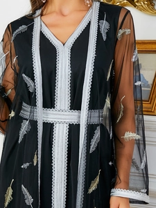 Close-up detail of silver lace trim and feather embroidery on elegant black tulle robe
