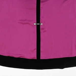 Detail of fuchsia satin dress with black velvet trim and crystal rhinestone embellishment