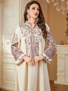 Détail de broderie de paillettes colorées sur une robe kaftan beige ethnique à col en V