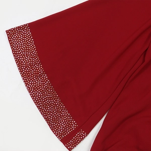 Detail of red chiffon robe featuring multiple rows of sparkling silver rhinestones on the cuff