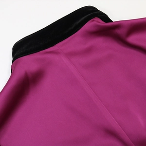 Detailed view of magenta satin neckline with elegant black velvet trim and fine stitching
