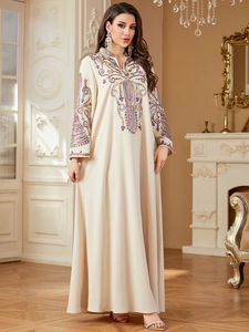 Détail de la broderie ethnique colorée sur robe longue bohème crème à manches longues