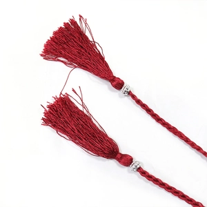 Close-up of two deep burgundy tassels with silver metal beads and woven rope details
