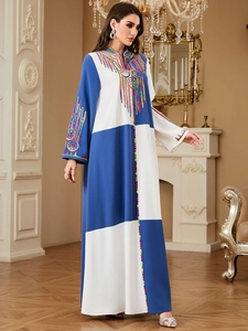 Close-up of ethnic multi-color embroidery and beadwork on a blue-white kaftan dress