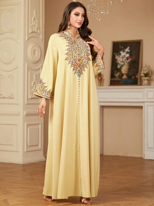 Détail de broderie florale multicolore sur une robe caftan Jalabiya jaune à manches