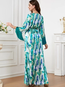 Détail de robe longue élégante à manches longues avec franges vertes et imprimé
