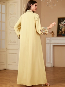 Détail de la broderie florale multicolore sur l'encolure d'une longue robe caftan jaune
