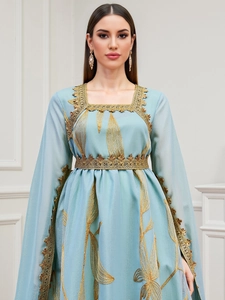 Close-up of golden wheat embroidery and delicate lace details on light blue chiffon dress
