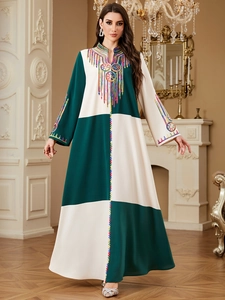 Detail of colorful embroidery on the collar and cuffs of a green patchwork maxi dress