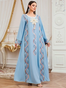 Robe longue bleu clair brodée avec accents floraux et glands dans un décor de palais