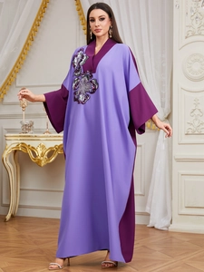 Detailed view of sequin flower embroidery and contrast purple trim on the v-neck kaftan