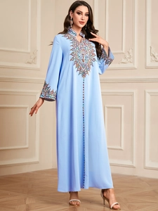 Détail de la broderie géométrique colorée sur le col et la poitrine d'une robe caftan bleue