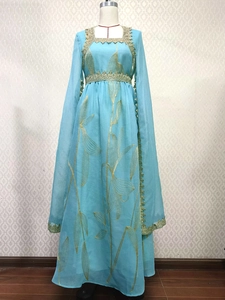 Detail of light blue embroidered dress featuring golden lace trim and leaf patterns