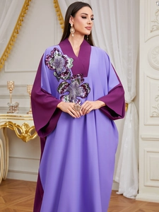 Detail of sequin floral embroidery and color-block stitching on a purple V-neck kaftan
