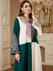 Detailed close-up of colorful embroidery and color-block stitching on the kaftan dress