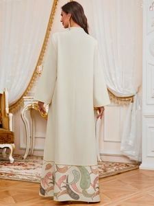 Détail de la broderie tribale sur l'ourlet d'une robe jalabiya crème à manches longues