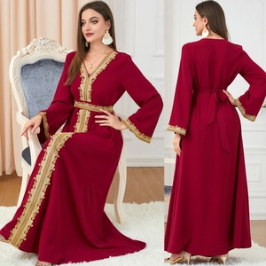 Detail of burgundy maxi dress featuring intricate gold embroidery on cuffs and waist
