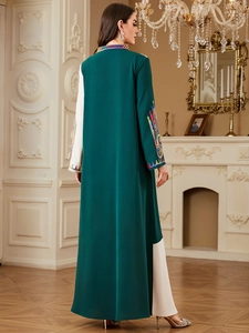 Close-up of elegant embroidery on deep green and white contrast long sleeve maxi dress
