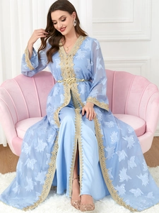 Detail of light blue Kaftan with gold embroidery and floral patterns on a pink shell sofa