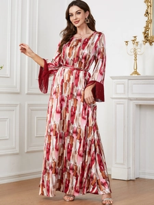 Détail des poignets à pompons rouges et imprimé abstrait sur une robe longue élégante