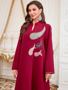 Détail de la robe jalabiya bordeaux avec broderie paisley dorée complexe sur la poitrine