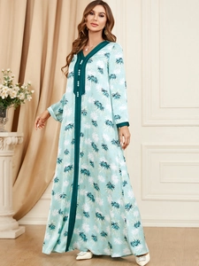 Detail of V-neckline with green trim and pearl buttons on blue botanical leaf print dress