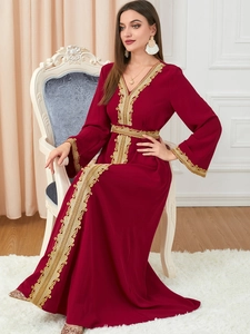 Close-up of golden vintage embroidery on a wine red long-sleeved elegant dress