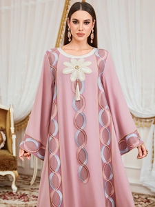 Détail d'une robe Abaya rose clair montrant l'applique florale et les motifs ondulés colorés