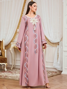 Détail de la broderie florale et des glands beiges sur le caftan rose à manches longues