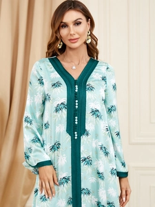 Detail view of the V-neckline with green embroidery and palm leaf print on light silk fabric