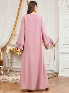 Détail de broderie géométrique florale sur les manches d'une robe kaftan rose