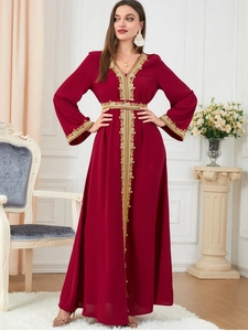 Close-up of golden lace embroidery and V-neck details on a long dark red kaftan dress