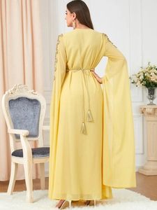 Detailed view of yellow chiffon kaftan with sequined shoulders and cape sleeves