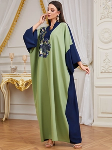 Close-up of olive and navy kaftan featuring sequin floral embroidery and batwing sleeves
