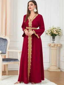 Detail of gold embroidery on a burgundy long-sleeved kaftan dress with elegant V-neck